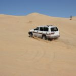Jeep fährt auf eine Sanddüne
